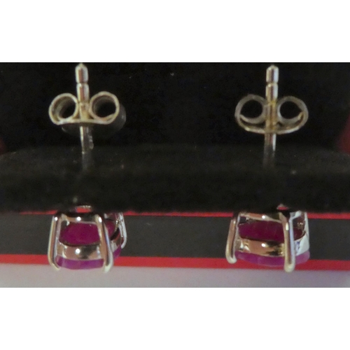 119 - A pair of claw set ruby earrings in white metal mounts 