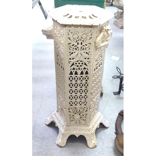 141 - An early 20thC cream painted, cast iron ecclesiastically inspired tower stove, raised on splayed fee... 