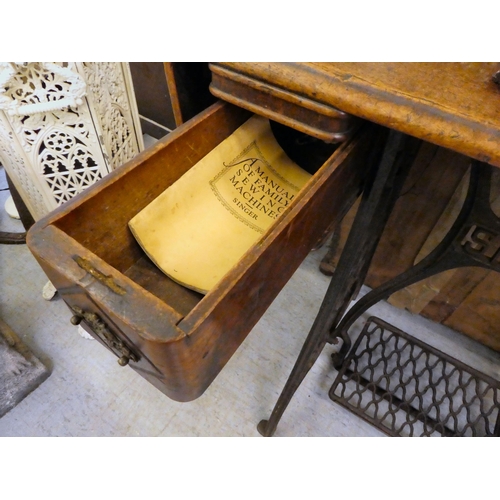 151 - A late Victorian Singer manual sewing machine, model.no.15128569, in a mahogany and cast iron treadl... 