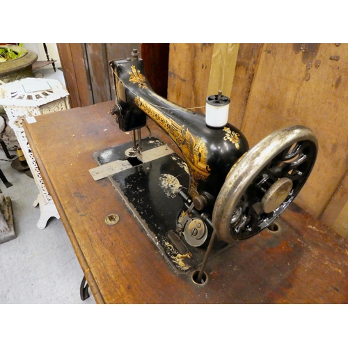 151 - A late Victorian Singer manual sewing machine, model.no.15128569, in a mahogany and cast iron treadl... 