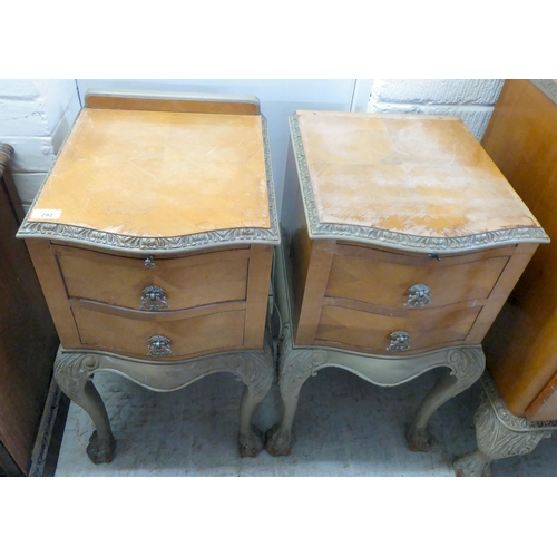 292 - A pair of mid 20thC crossbanded, bleached mahogany, two drawer bedside chests, raised on carved cabr... 