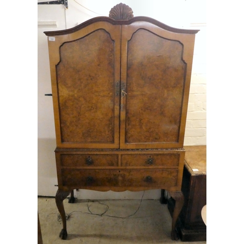 310 - A 20thC quarter veneered walnut two-part cabinet cocktail with a pair of shaped panelled doors, over... 