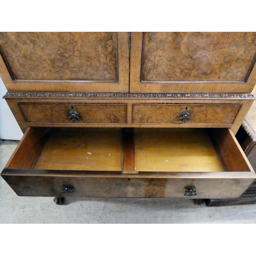 310 - A 20thC quarter veneered walnut two-part cabinet cocktail with a pair of shaped panelled doors, over... 