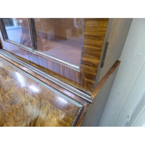 319 - A 20thC crossbanded, walnut veneered bureau bookcase, the upper section with a pair of glazed doors ... 