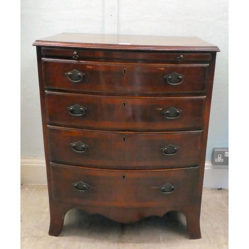 38 - A modern mahogany bowfront dressing chest with a brushing slide and four long drawers, raised on bra... 