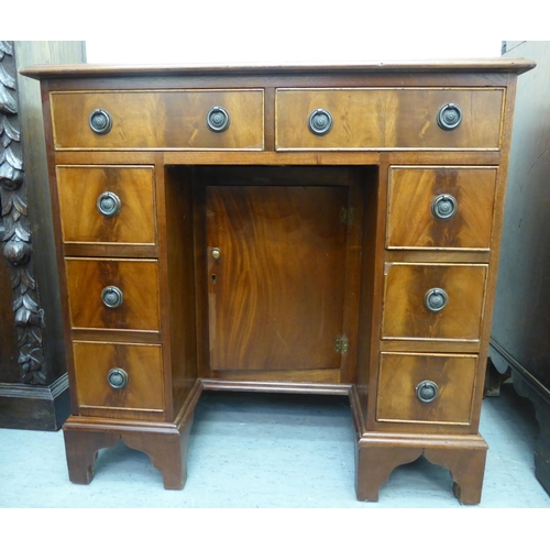 45 - A modern mahogany kneehole desk with a central cupboard and eight drawers, raised on bracket feet&nb... 