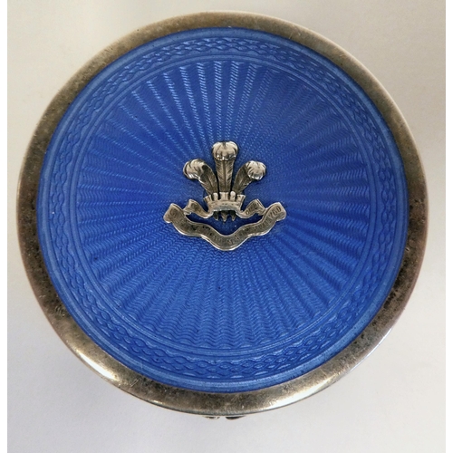 6 - A silver circular powder compact with a hinged, engine turned blue enamel lid and an applied emblem ... 