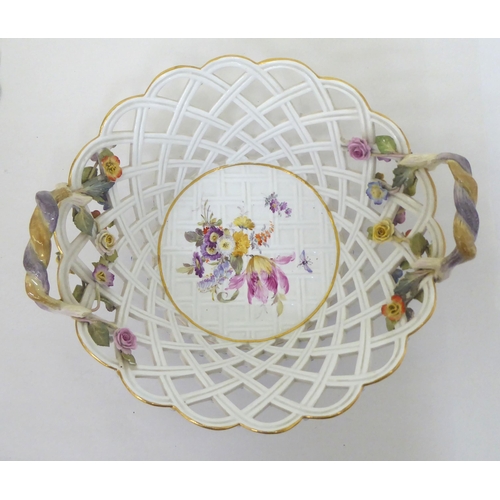 60 - A Meissen porcelain centrepiece fruit bowl with twin handles, over a latticeworked design basket, de... 