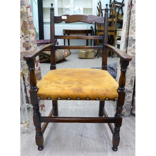 110 - A 19thC style stained beech framed, low, open arm, ladder back chair with a studded and aged, hide u... 