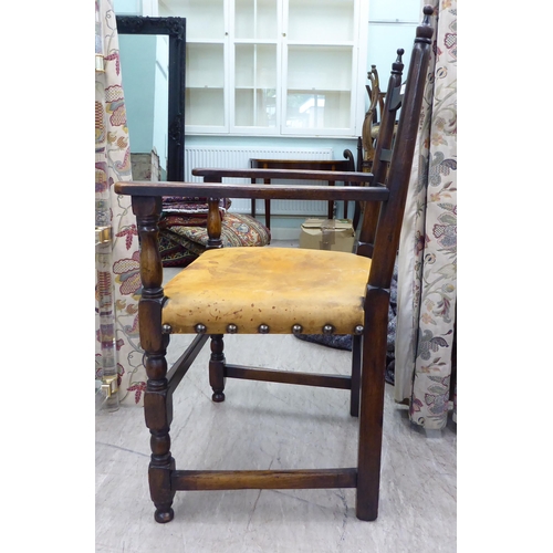 110 - A 19thC style stained beech framed, low, open arm, ladder back chair with a studded and aged, hide u... 