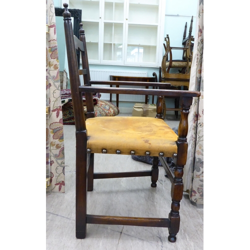 110 - A 19thC style stained beech framed, low, open arm, ladder back chair with a studded and aged, hide u... 