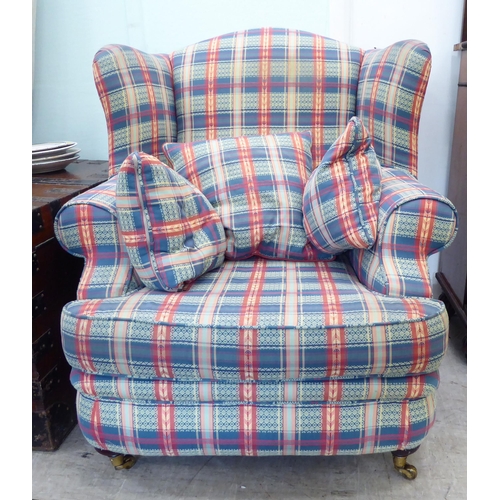 120 - A modern wingback armchair, upholstered in multi-coloured chequered fabric with a loose cushion, two... 