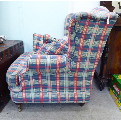 120 - A modern wingback armchair, upholstered in multi-coloured chequered fabric with a loose cushion, two... 