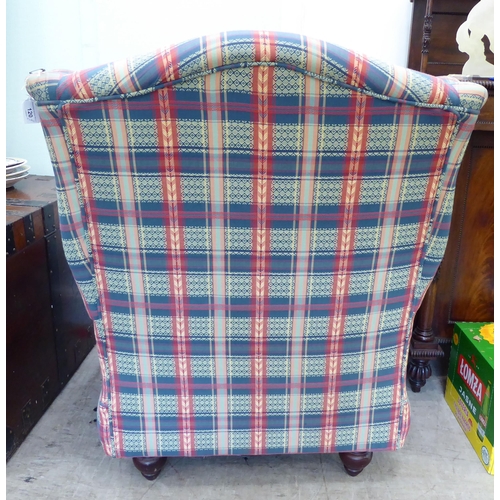 120 - A modern wingback armchair, upholstered in multi-coloured chequered fabric with a loose cushion, two... 