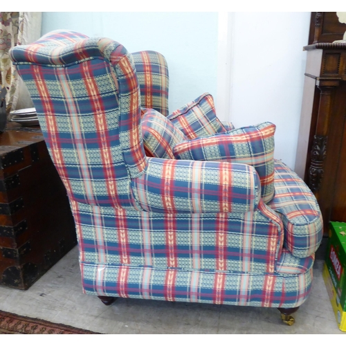 120 - A modern wingback armchair, upholstered in multi-coloured chequered fabric with a loose cushion, two... 