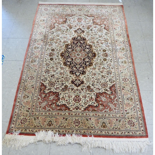 132 - A Persian part silk rug with dense floral decoration, on a beige and red ground  66