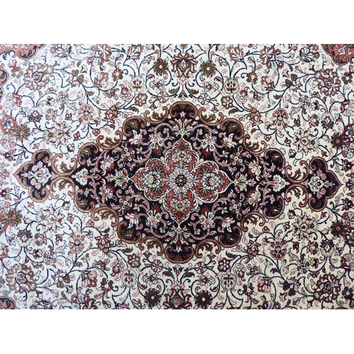 132 - A Persian part silk rug with dense floral decoration, on a beige and red ground  66