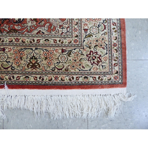 132 - A Persian part silk rug with dense floral decoration, on a beige and red ground  66