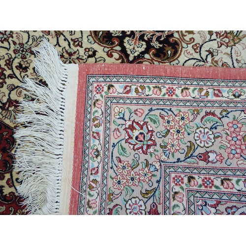 132 - A Persian part silk rug with dense floral decoration, on a beige and red ground  66