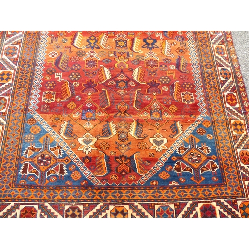 198 - A Persian rug, decorated with repeating stylised designs, on a mainly red ground  64