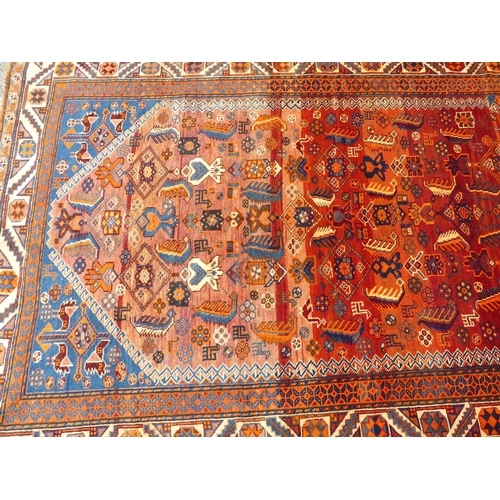 198 - A Persian rug, decorated with repeating stylised designs, on a mainly red ground  64