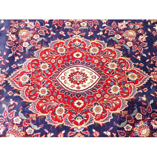 239 - An Iranian carpet, profusely decorated with floral and foliage designs, on a mainly dark blue and re... 