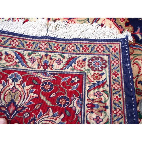 239 - An Iranian carpet, profusely decorated with floral and foliage designs, on a mainly dark blue and re... 