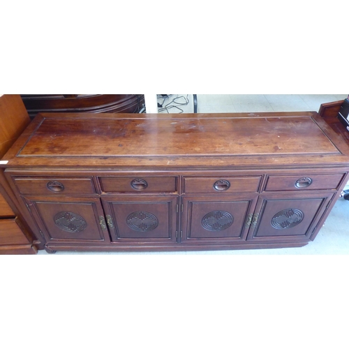 245 - A 20thC Chinese fruitwood dresser with four in-line drawers, over four panelled doors, raised on sha... 