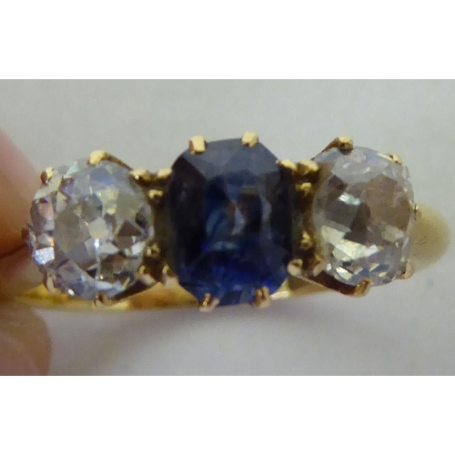 254 - A yellow metal claw set ring, set with a central amethyst, flanked by two diamonds  boxed