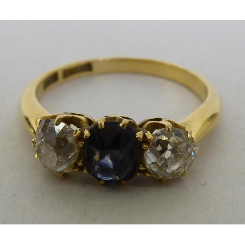 254 - A yellow metal claw set ring, set with a central amethyst, flanked by two diamonds  boxed