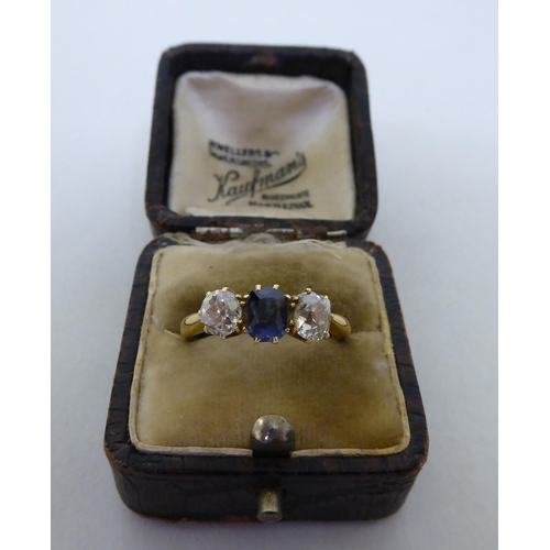 254 - A yellow metal claw set ring, set with a central amethyst, flanked by two diamonds  boxed