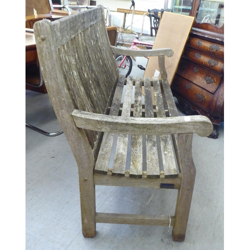 288 - A weathered, slatted teak garden bench, raised on square legs  60