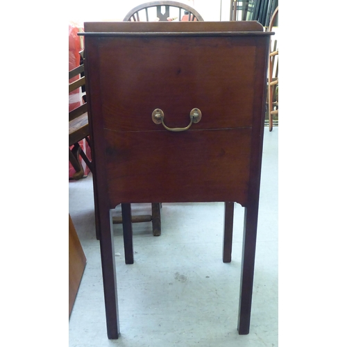 290 - An Edwardian mahogany pot cupboard with a low gallery, over a door and drawer, raised on square legs... 