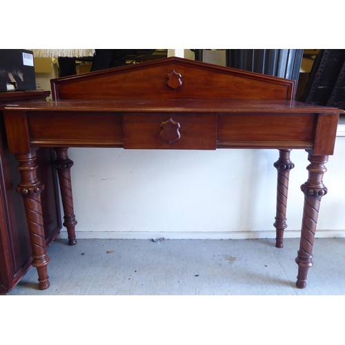 324 - A late Victorian mahogany serving side table with an arched upstand, over a central frieze drawer, r... 