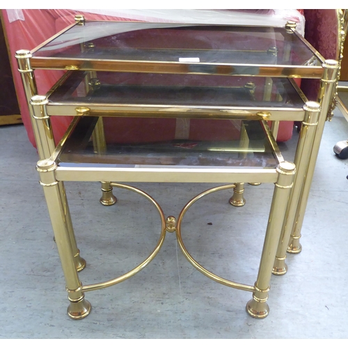 332 - A modern nesting set of three gilt metal framed occasional tables, each with a smoked glass top, rai... 