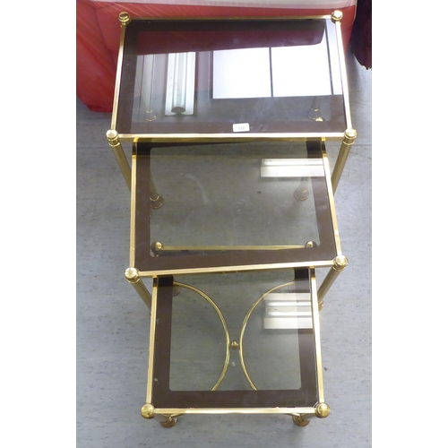 332 - A modern nesting set of three gilt metal framed occasional tables, each with a smoked glass top, rai... 