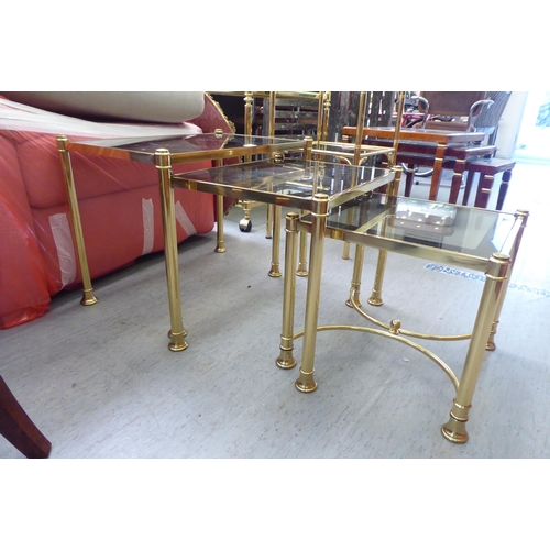 332 - A modern nesting set of three gilt metal framed occasional tables, each with a smoked glass top, rai... 