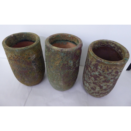 37 - A set of three naturalistically finished and randomly painted terracotta pots of tapered cylindrical... 