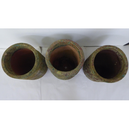 37 - A set of three naturalistically finished and randomly painted terracotta pots of tapered cylindrical... 