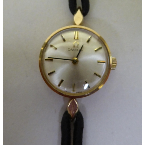 44 - A lady's Omega 9ct gold, round cased wristwatch, faced by a baton dial, on two strand hide strap&nbs... 