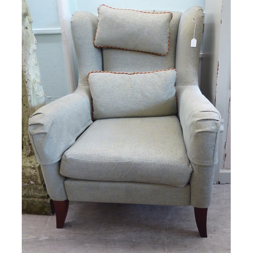 45 - A Wesley Barrell wingback armchair, upholstered in pale blue/stone coloured fabric with a cushioned ... 