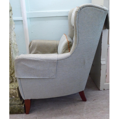 45 - A Wesley Barrell wingback armchair, upholstered in pale blue/stone coloured fabric with a cushioned ... 