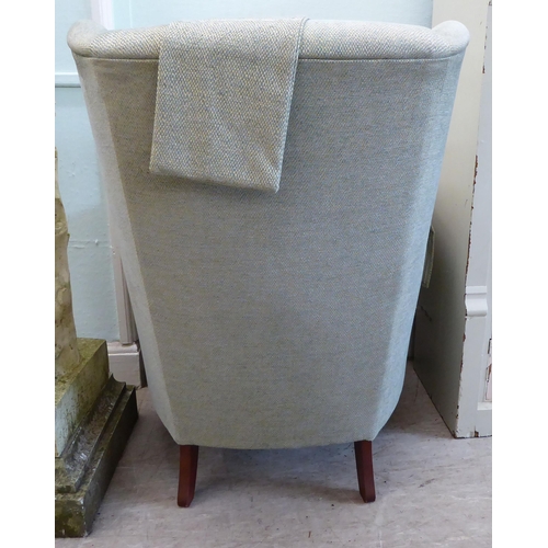 45 - A Wesley Barrell wingback armchair, upholstered in pale blue/stone coloured fabric with a cushioned ... 