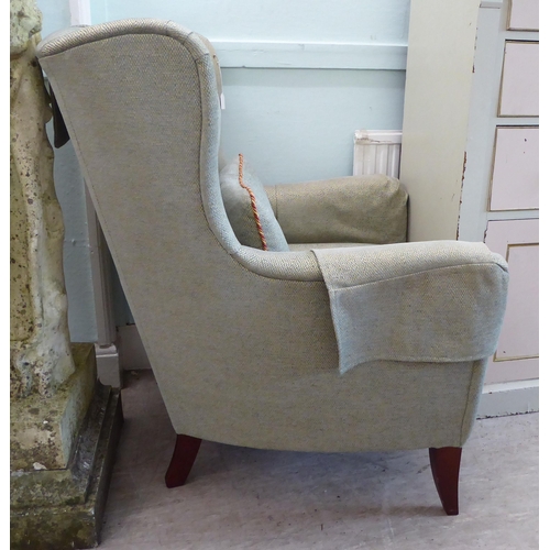 45 - A Wesley Barrell wingback armchair, upholstered in pale blue/stone coloured fabric with a cushioned ... 