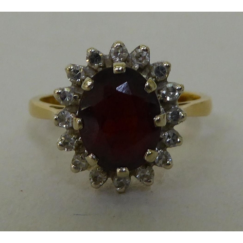 55 - An 18ct gold cluster ring, claw set with a garnet, surrounded by diamonds