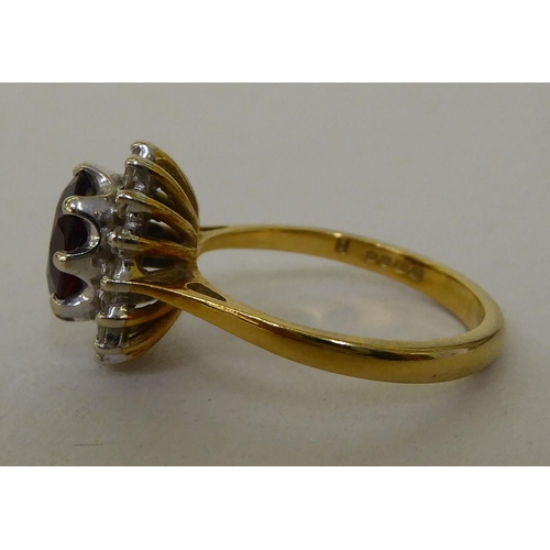 55 - An 18ct gold cluster ring, claw set with a garnet, surrounded by diamonds