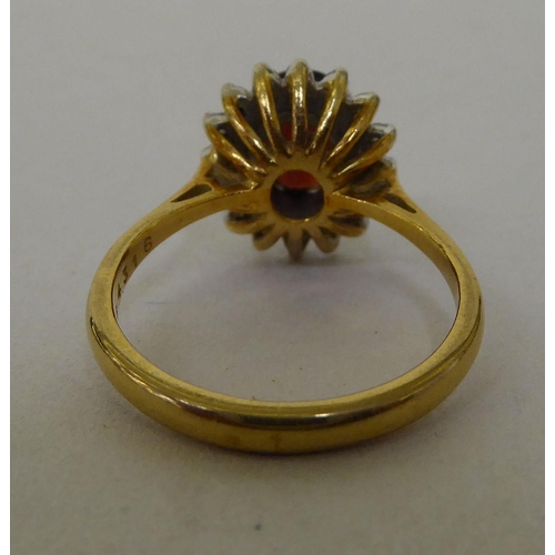 55 - An 18ct gold cluster ring, claw set with a garnet, surrounded by diamonds