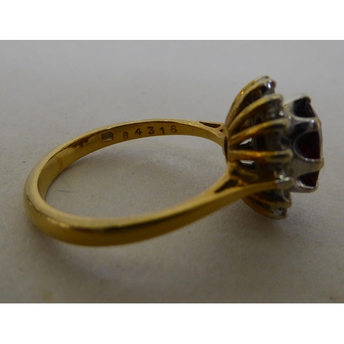 55 - An 18ct gold cluster ring, claw set with a garnet, surrounded by diamonds