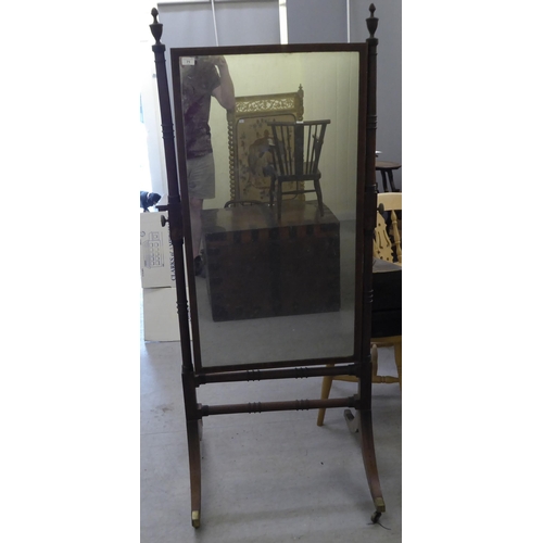 71 - A Regency mahogany cheval mirror with turned uprights, raised on splayed legs with casters  67