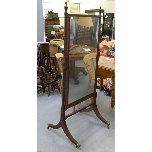 71 - A Regency mahogany cheval mirror with turned uprights, raised on splayed legs with casters  67